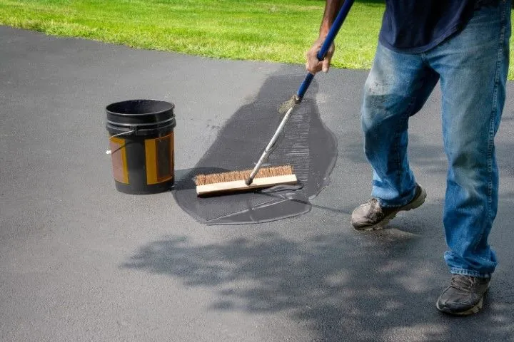 Technician sealing concrete driveway surface in Grandview, MO